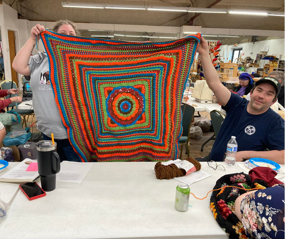 Members proudly displaying their brightly colored handmade blanket